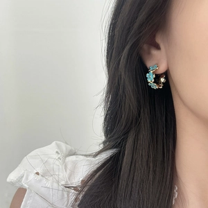 Eleganti orecchini a cerchio a C dorati con fiori in smalto azzurro su modella