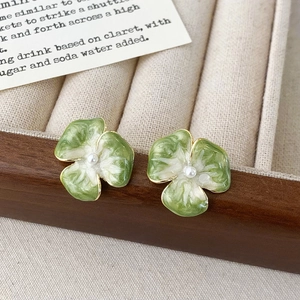 Dettaglio degli orecchini floreali in smalto verde e bianco con bordi dorati