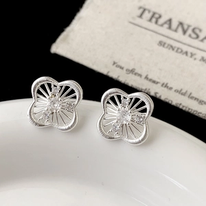 Close-up of silver hollow floral stud earrings with sparkling zircon stones in a tray