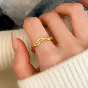 Elegant gold wavy twist ring for women worn on hand with a soft white sweater background