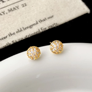 Gros plan de boucles d'oreilles dorées avec sphères en zircons blancs sertis pavé