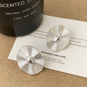 Macro shot of silver textured oval stud earrings with smooth center inset on card
