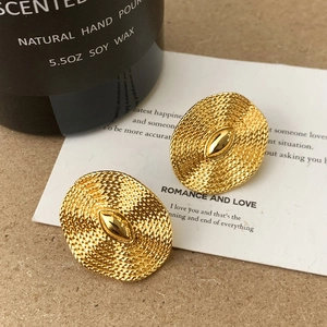 Detail of golden oval stud earrings with woven metal texture and vintage design