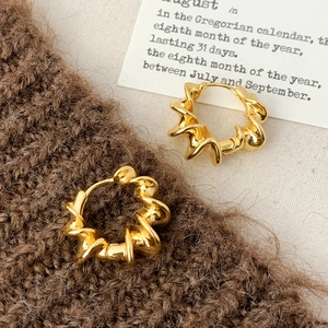 Détail de boucles d'oreilles dorées torsadées sur tricot avec texture spirale