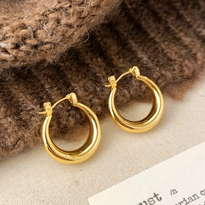 Vue macro de boucles d'oreilles créoles dorées polies avec fermoir à charnière