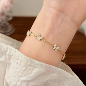 Elegant gold butterfly bracelet with pavé cubic zirconia worn on wrist with floral accents