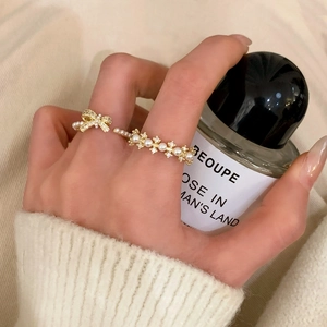 Elegant gold pearl ring set with bow and flower designs featuring sparkling crystals