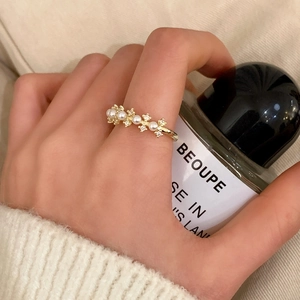 Elegant gold pearl ring with pavé zircons worn by a model holding a perfume bottle