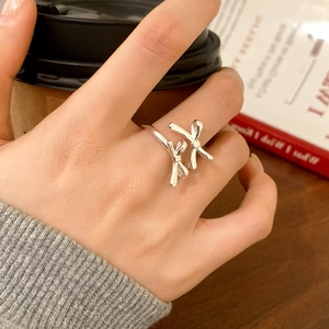 Detail of silver double bow open ring on finger in a cozy cafe lifestyle scene