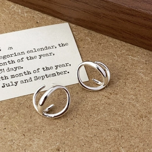 Close-up of minimalist silver intertwined double hoop earrings on a kraft paper background