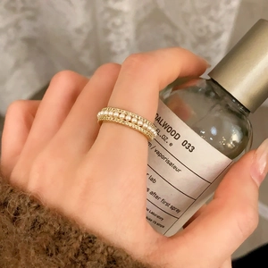 Gros plan d'une bague dorée avec rangée de perles et bordure perlée portée au doigt