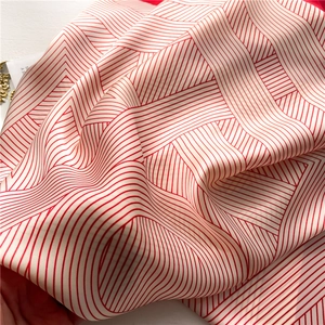 Detailed close-up of red and white geometric stripe silk scarf with smooth satin texture