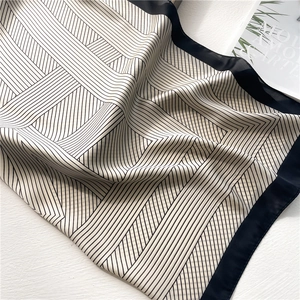 Detailed view of geometric striped silk scarf with black satin border and soft texture