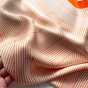 Detailed close-up of orange and white striped silk scarf with elegant satin finish