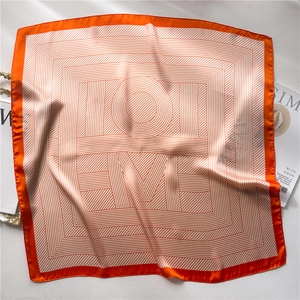 Detail view of the striped silk square scarf featuring orange borders and brand lettering