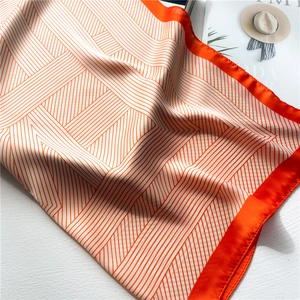 Macro detail of a square silk scarf with vibrant orange and white geometric stripes