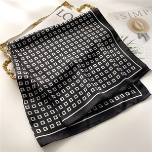 Close-up of luxury satin scarf with G-letter patterns on decorative golden tray