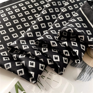 Detail of silk scarf with G-letter patterns showing soft texture and glossy finish