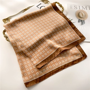 Detail of silk scarf with G-pattern and brown border on a golden vintage tray