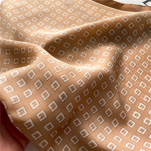Detail of silk-like scarf showing luxury geometric G pattern and satin texture