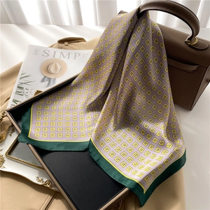 Detail of silk-feel scarf with yellow G-pattern on lilac background over leather bag