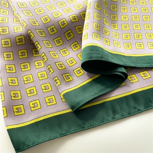 Macro shot of silk scarf showing lavender fabric with G pattern and green borders