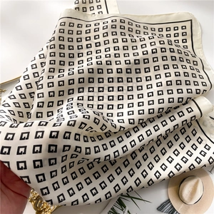 Macro shot of white silk scarf with black G pattern and elegant black border finish