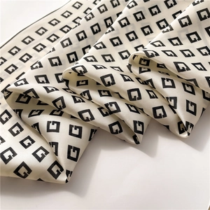 Detail of silk-like scarf with G-letter geometric pattern showing smooth satin texture