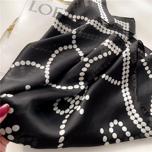 Elegant black and white polka dot silk scarf with chain pattern on a minimalist background
