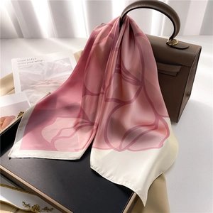 Elegant pink floral silk scarf with rose pattern draped on a designer leather handbag