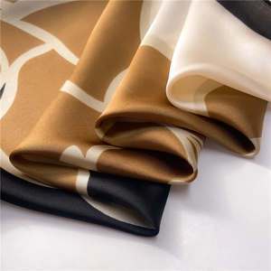 Macro detail of silk scarf showing brown and white geometric patchwork and satin texture
