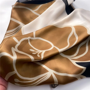 Detailed macro view of floral satin scarf showing champagne and navy blue silk texture