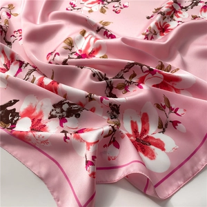 Primer plano de un pañuelo de seda rosa con estampado de magnolia y textura satinada