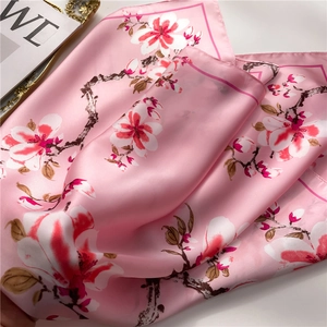 Primer plano de un pañuelo de seda rosa con textura suave y elegantes motivos de magnolia