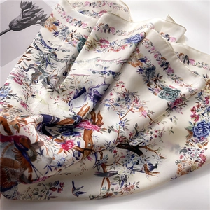 Elegant silk scarf featuring bird and floral prints on a creamy white satin background