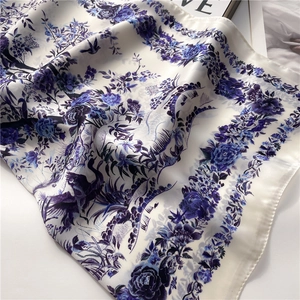 Detail of silk scarf with blue floral and bird patterns on a pearl white background