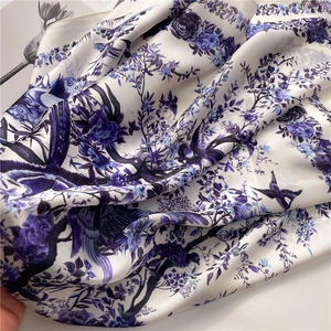 Close-up of silky floral scarf featuring elegant blue bird patterns and smooth texture
