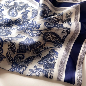 Detail of silk-like blue paisley square scarf showing satin luster and hemmed edges