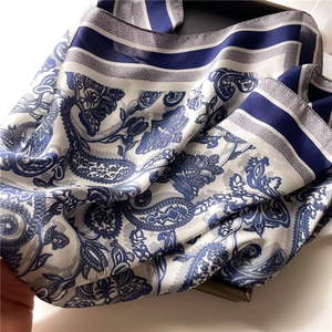 Close-up of navy paisley pattern on satin square scarf with smooth silk texture