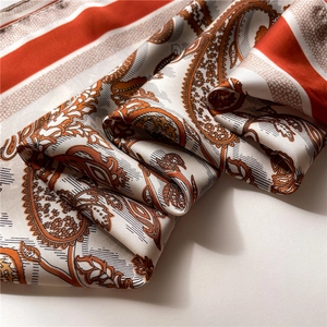 Detailed view of orange and brown paisley patterns on premium silk-touch square scarf