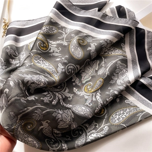 Close-up showing the elegant draping of a silk paisley square scarf with grey and black patterns