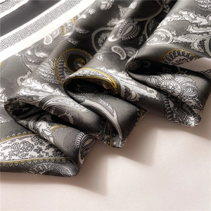 Macro detail showing the glossy paisley pattern on a premium grey satin square scarf