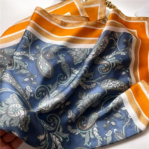 Detail of silk-texture square scarf with paisley pattern and orange contrast edges