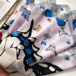 Détail d'un carré de soie aux motifs papillons avec un drapé élégant sur fond blanc