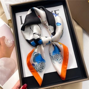 Gros plan d'un foulard carré en satin avec imprimés papillons dans un coffret cadeau