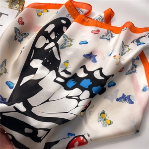 Détail d'un foulard en soie avec motifs papillons et bordures orange vif
