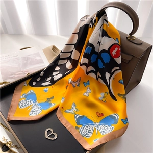 Foulard en soie jaune avec motif papillon noué sur un sac en cuir à la lumière naturelle