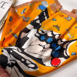 Détail macro du foulard en soie orange avec imprimé papillon et texture satinée lisse