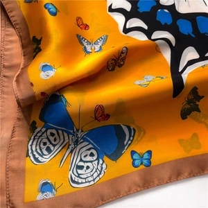 Détail d'un foulard en soie avec imprimés papillons et texture satinée orange brillante