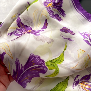Detailed view of silk texture square scarf with purple iris flowers and green leaves